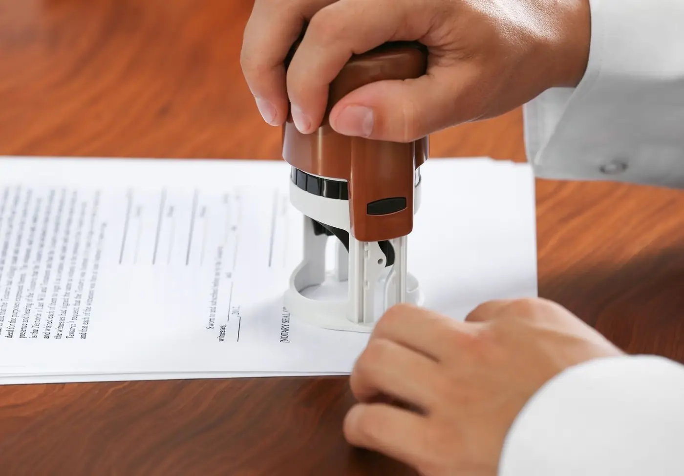 Close-up of a hand pressing a stamp onto a paper document