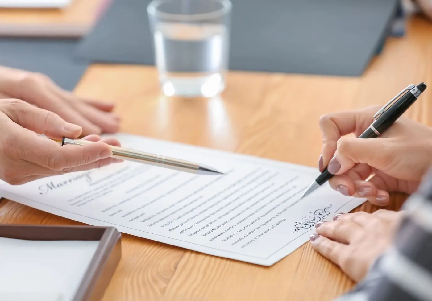 Two people signing documents at a table
