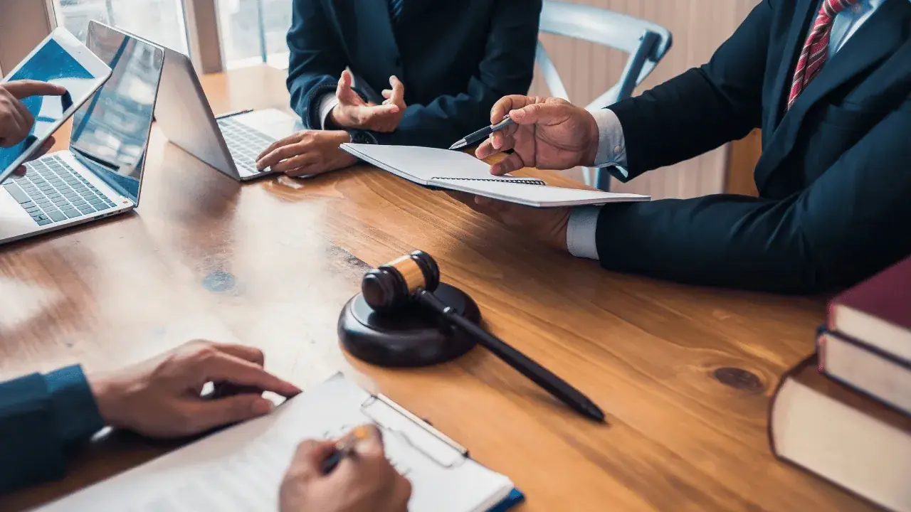Certified True Copy Attestation in Sharjah 4 People signing documents at a desk with a gavel