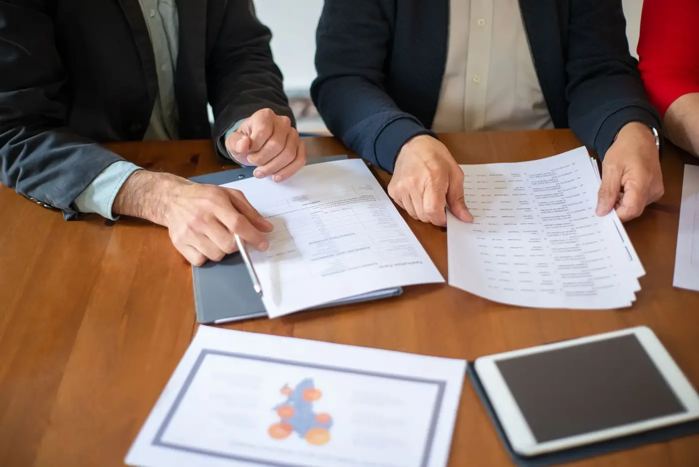 Certified True Copy Attestation in Sharjah 1 Two people comparing printed papers side by side on a wooden table