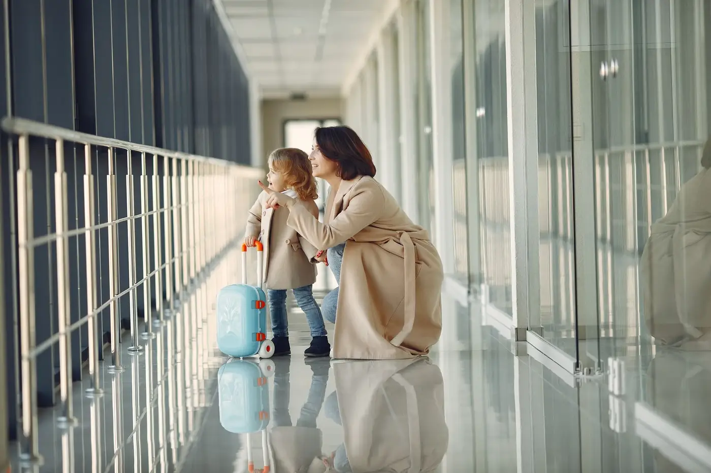 Child Travel Consent Form in the UAE 1 A mother and young child with a small suitcase in an airport corridor