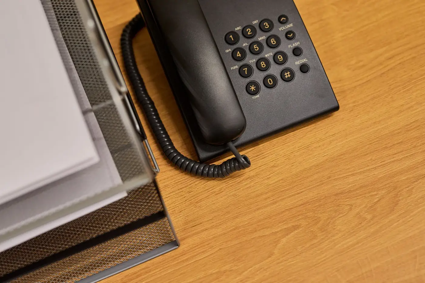 Contact us about your document 1 A black desk telephone beside a paper tray on a wooden desk