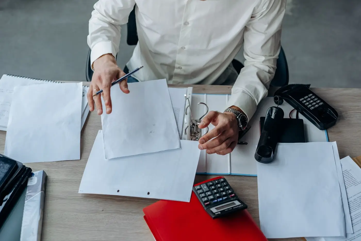 Corporate and Business Notary Services in Dubai 1 A man sorting company papers and a ring binder on an office desk
