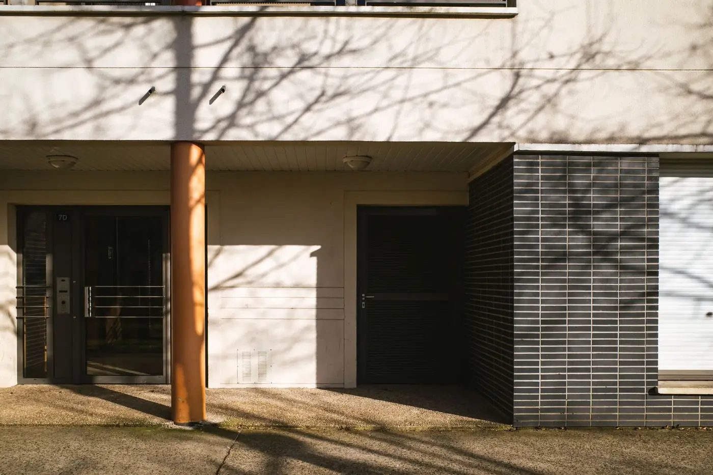 The front entrance of a residential apartment building in afternoon sun