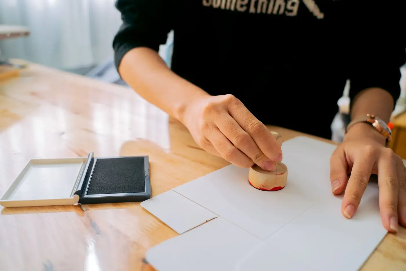Notary public fees in Dubai: what you pay and why 4 A hand pressing a round stamp onto white paper beside an ink pad