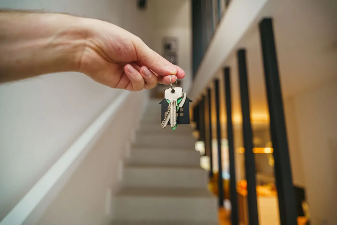 Gift Deed in Dubai: Gifting Property to Family 1 A hand holding house keys on a house shaped key ring indoors