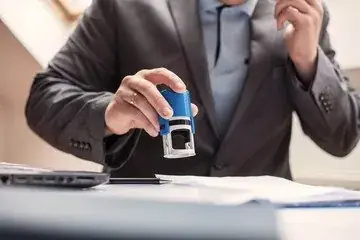 How to notarise a document in Dubai, step by step 1 A hand pressing a blue stamp onto a document