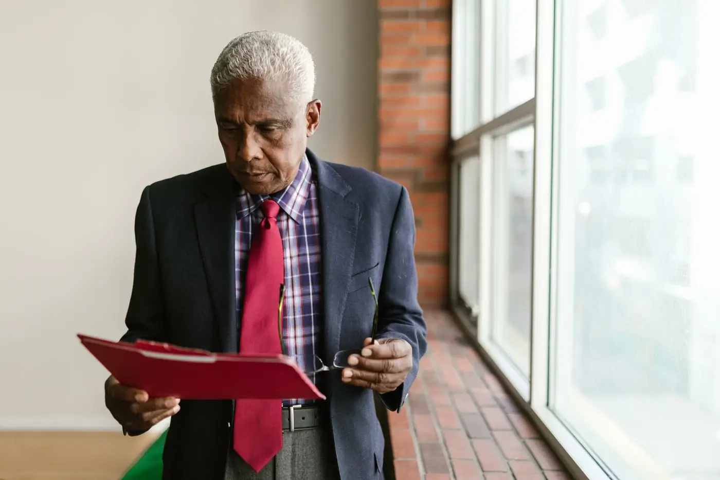 NOC Letter From Your Sponsor in the UAE 80 An older man reading papers in a red folder by a window