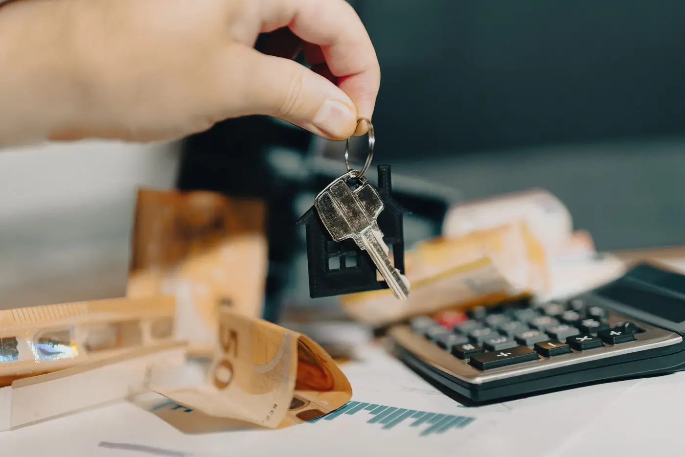 Eviction Notice in Dubai: The 12 Month Notice and How to Serve It 4 Hand holding house keys above a calculator, cash and rent paperwork