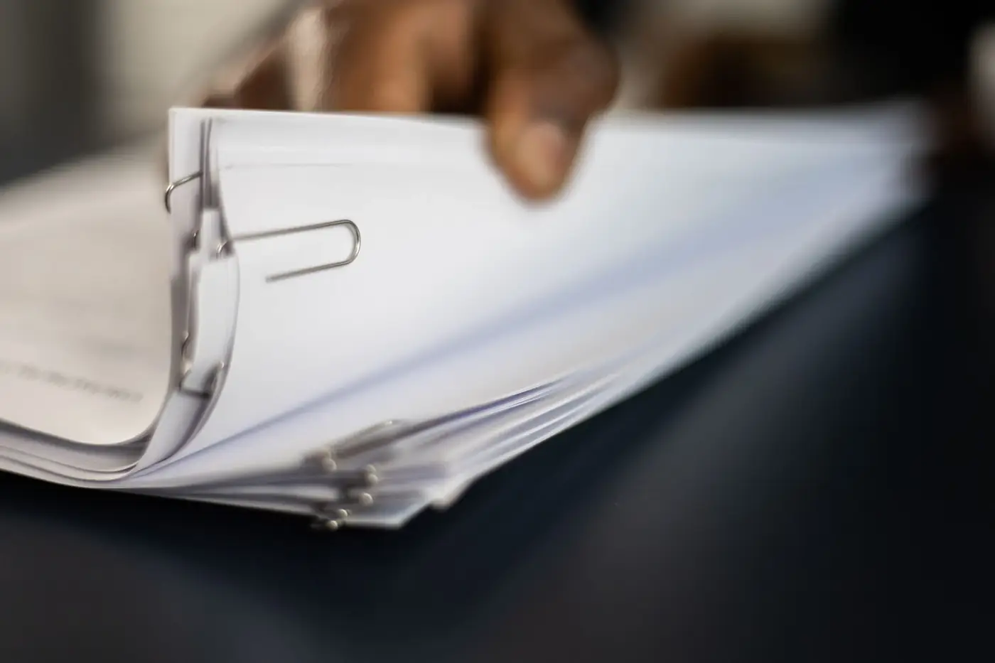 MOA Amendment in the UAE: Addendum to MOA 3 A hand lifting a thick stack of clipped papers from a desk