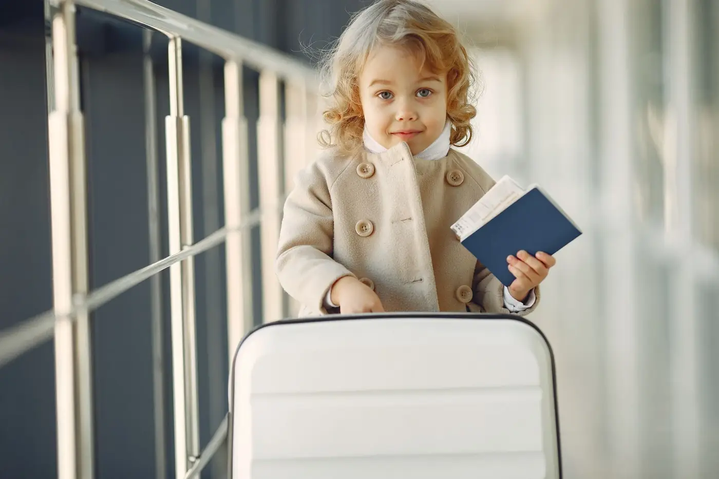 Child Travel Consent Form in the UAE 80 A young child holding a passport while pushing a white suitcase