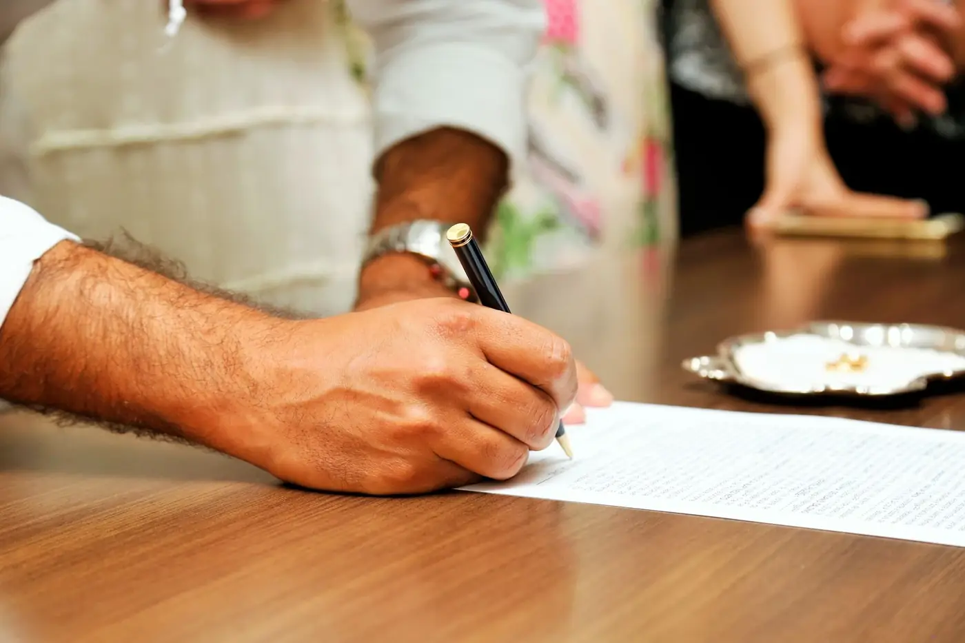 How to notarise a document in Dubai, step by step 2 A client signing a document at a desk in front of a notary