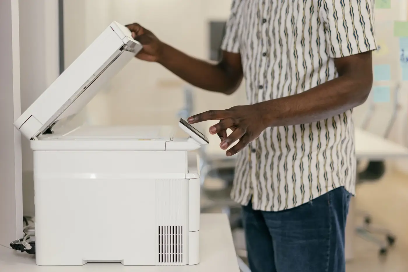 Certified True Copy Attestation in Sharjah 3 A man lifting the lid of an office photocopier to make a copy
