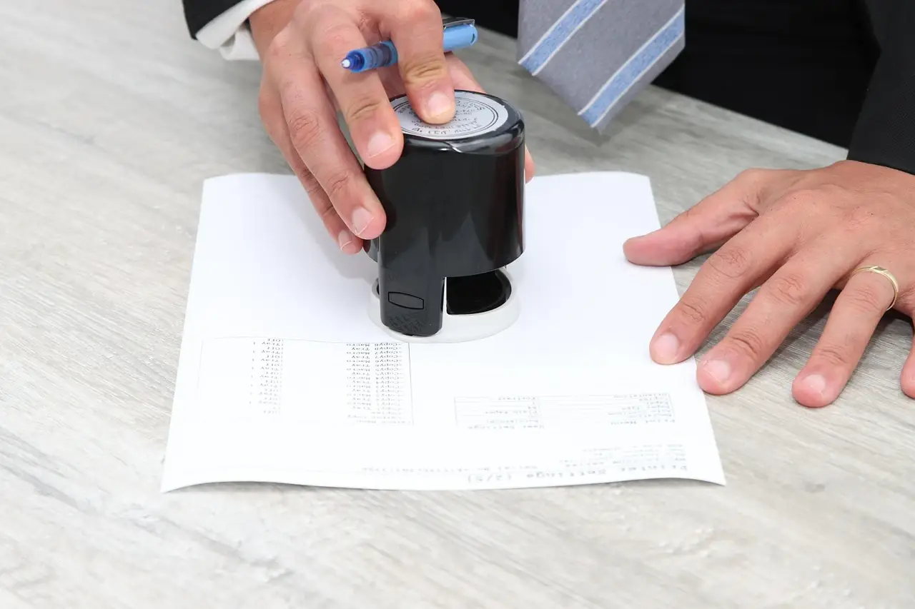 A hand pressing a self inking stamp onto a printed document