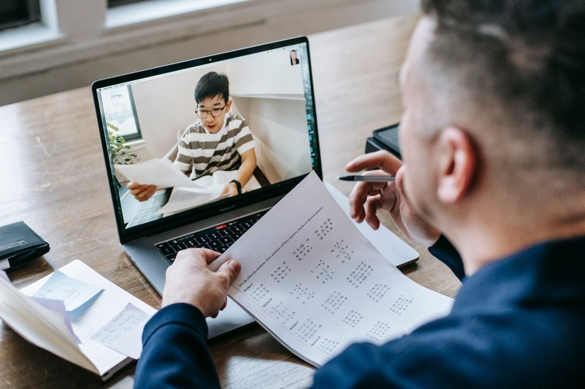 خدمات كاتب العدل الالكترونية دبي: كيف توثق مستندك عن بعد 2 رجل يمسك ورقة أثناء مكالمة فيديو على حاسوب محمول